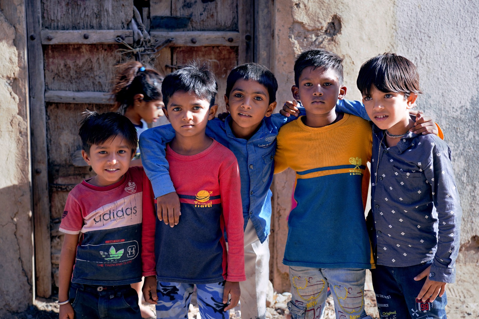 Five boys standing arm in arm outside their homes