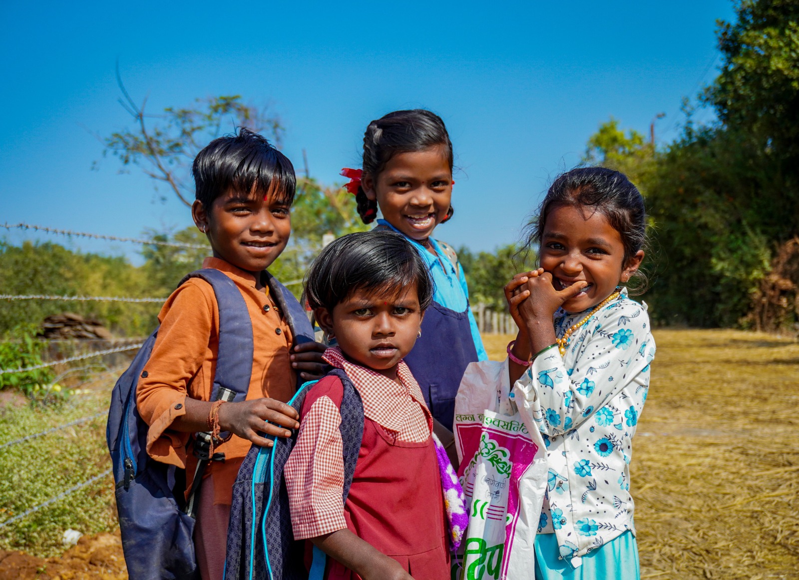 Four smiling children on their way home from school