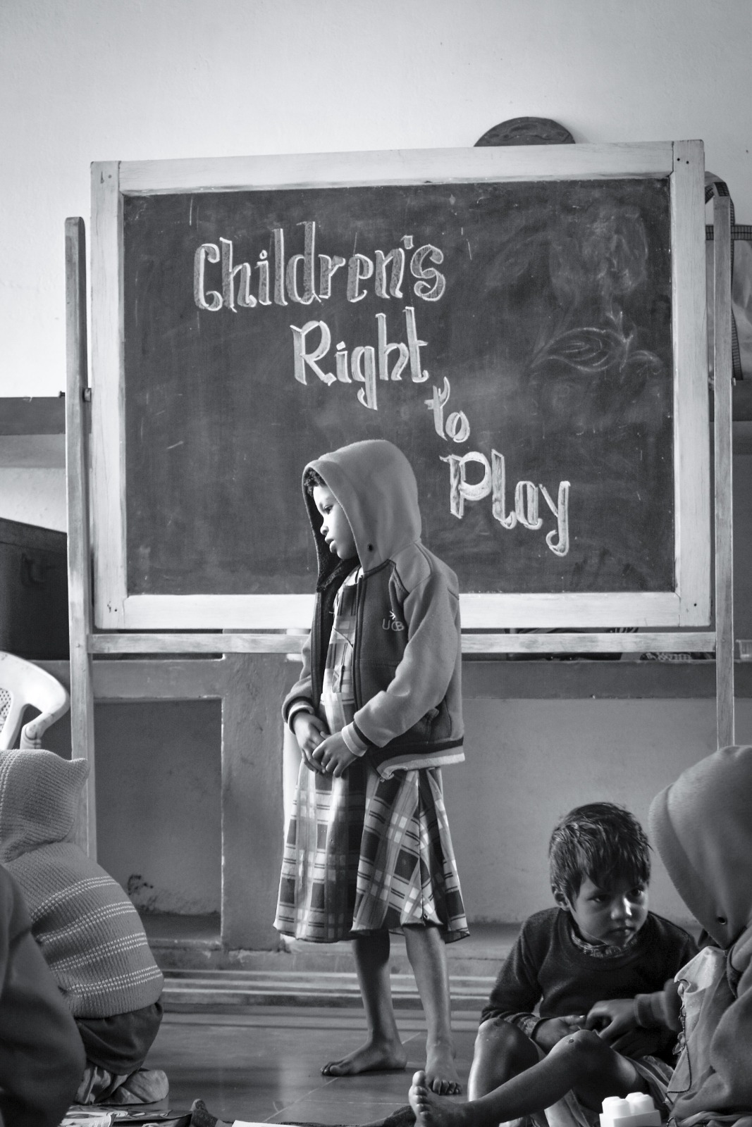 A young child in front of a blackboard reading &lsquo;Children&rsquo;s Right to Play&rsquo;
